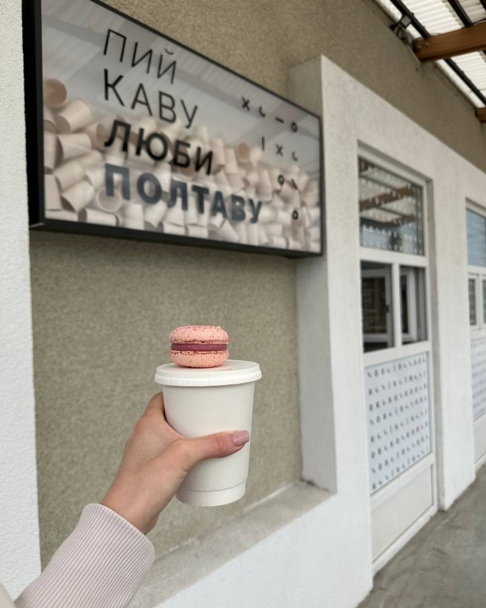Рожевий макарон на склянці кави під вивіскою Пий каву. Люби Полтаву.
